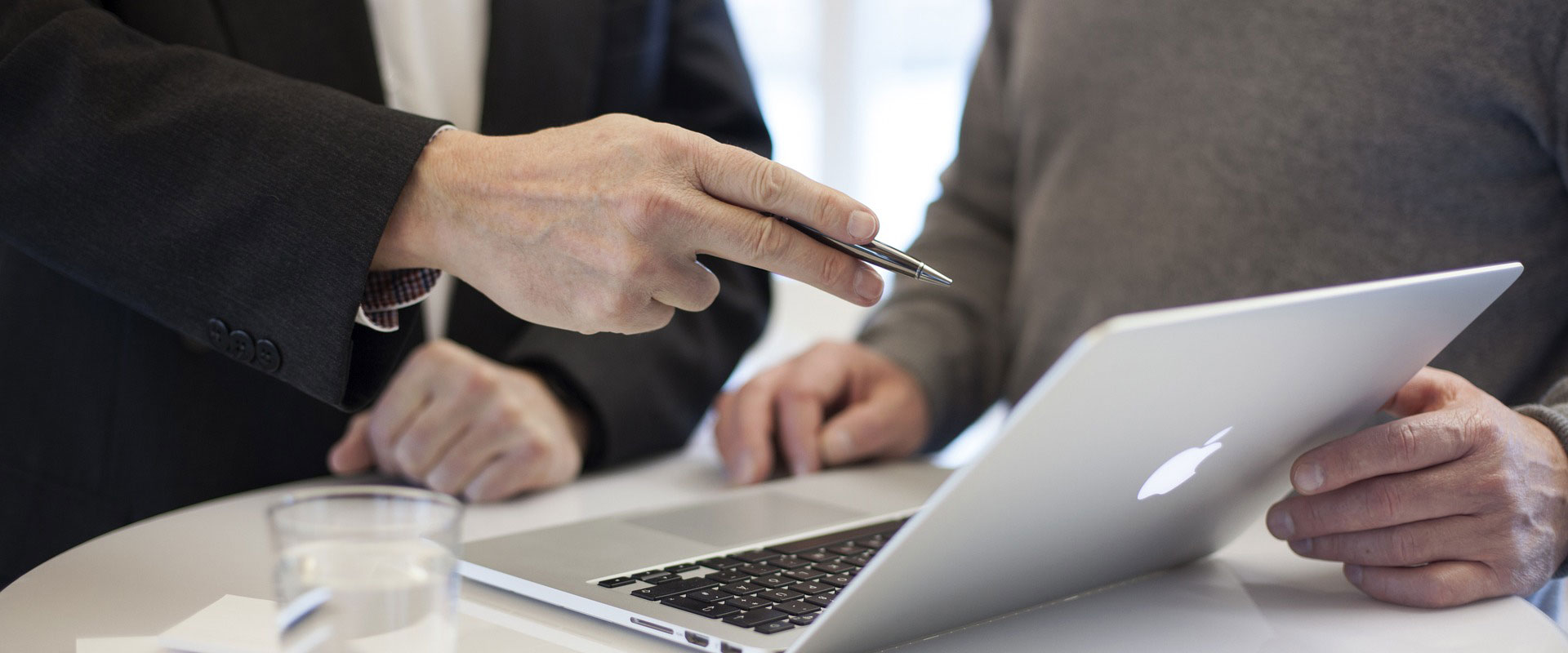 Two men in suits looking at laptop during Managed IT Services maintenance visit.