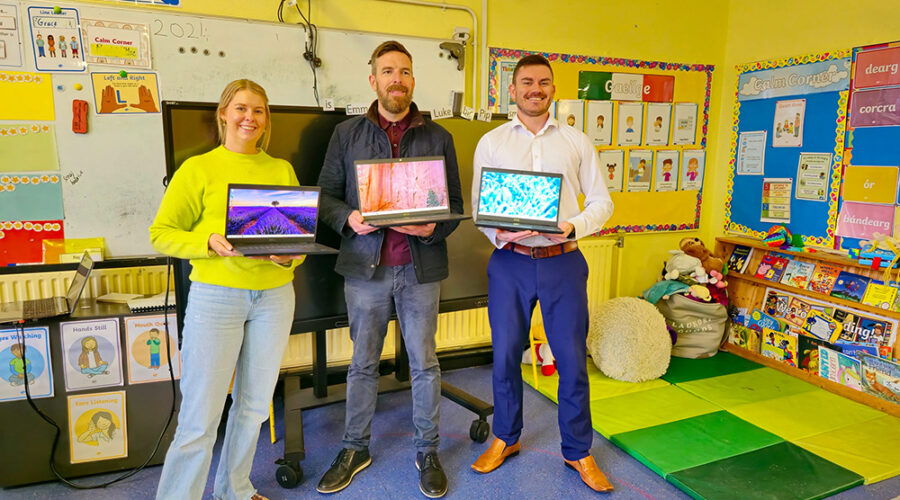 Three people posing with three open laptops.