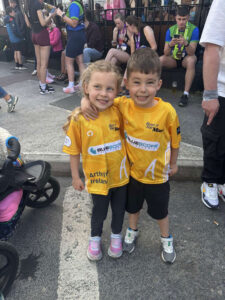 Two young children pose for a photo wearing yellow t-shirts with Bluescope logo.
