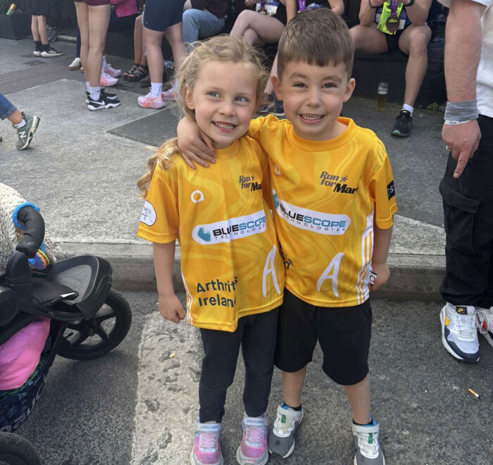 Two young children pose for a photo wearing yellow t-shirts with Bluescope logo.