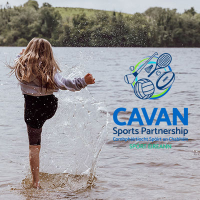 Young girl kicking water towards the Cavan Sports Partnership logo.